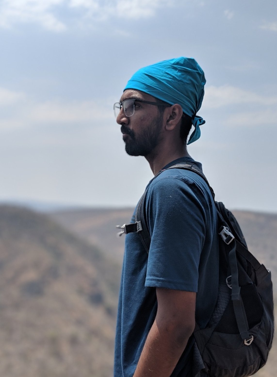 M1, founder of Odyssey Division, looking out over a mountain ridge with a backpack